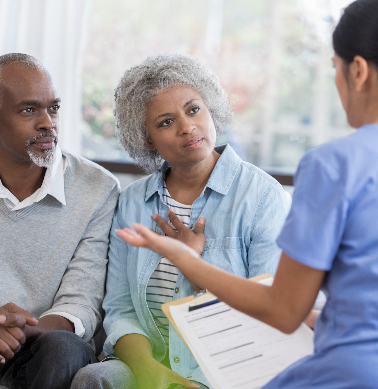 Mid adult female doctor gestures a she discusses a senior couple's health concerns.