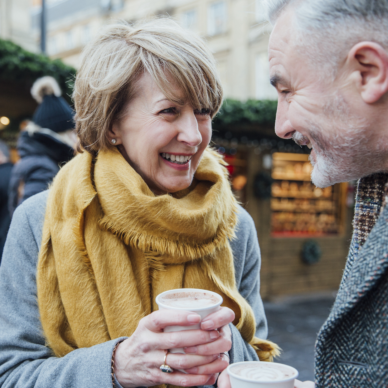 Mature couple are enjoying a cup of coffee as they explore the town christmas market.