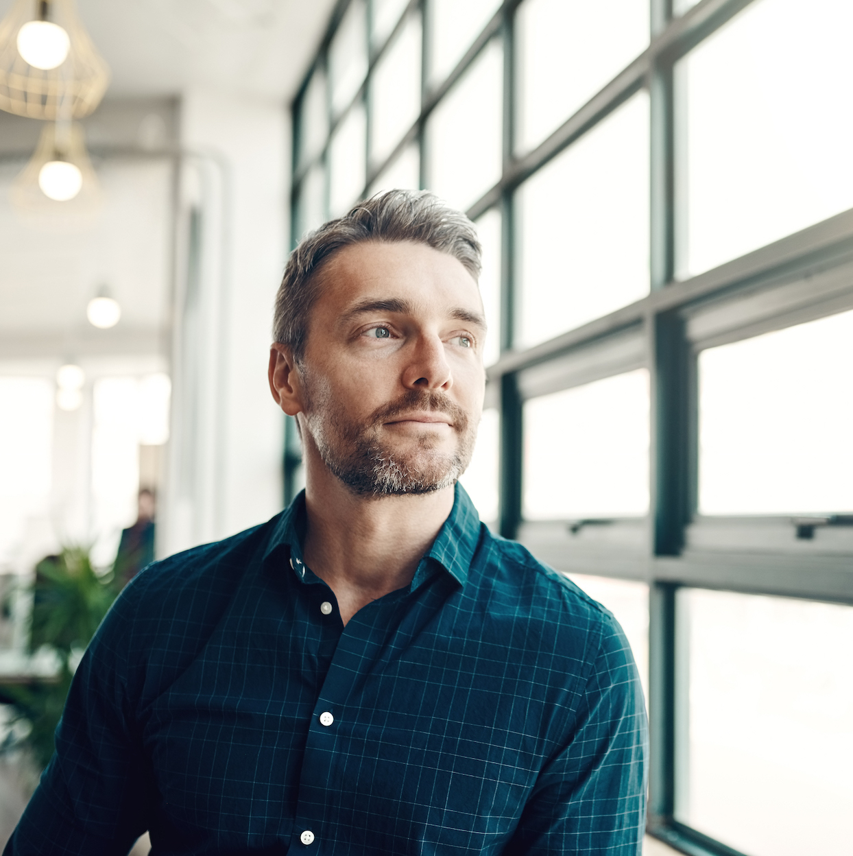 Shot of a mature businessman looking thoughtfully out of an office window